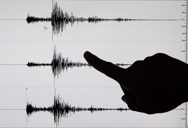 A Filipino Senior Science Research Specialist points to recorded tremors on a seismogram